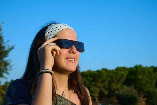 Portrait of a teenage girl watching a solar eclipse with protective glasses.