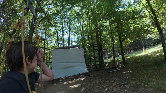 Boy Riding Zipline Rope Swing in Outdoor Adventure Park