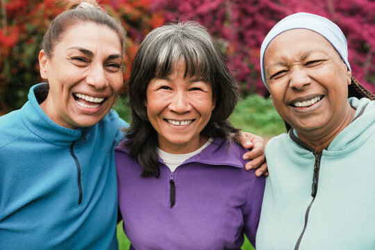 Happy senior women having fun together after yoga class outdoor - Multiracial mature female smiling on camera - Sport, friendship and healthy lifestyle concept - Main focus on asian person face