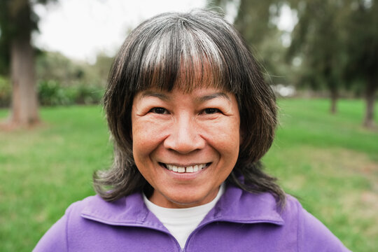 Happy senior asian woman smiling on camera after yoga class workout outdoor - Sport and healthy lifestyle concept
