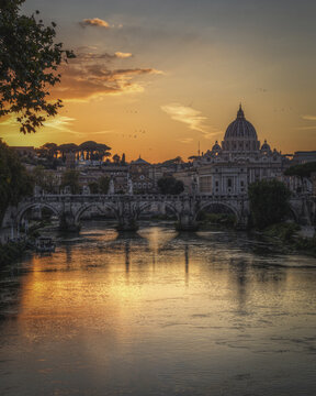 Roma, Lazio, Italy - 16 October 2021: View of Castel Sant'Angelo and St. Peter's Basilica at sunset with the Tiber River reflecting the golden light.