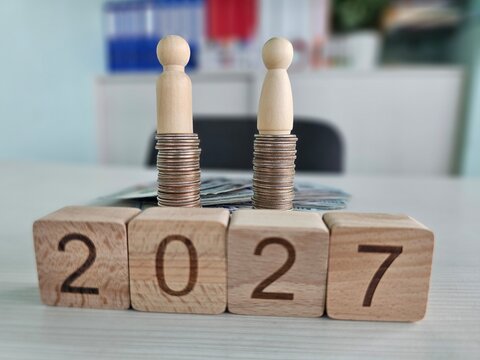 Stacks of coins and wooden figures represent financial growth