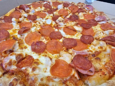 Freshly made pizza topped with pepperoni and cheese at a restaurant