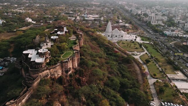 Aerial view of birla mandir temple and moti dungri fort on a hilltop in jaipur, india, showing city traffic