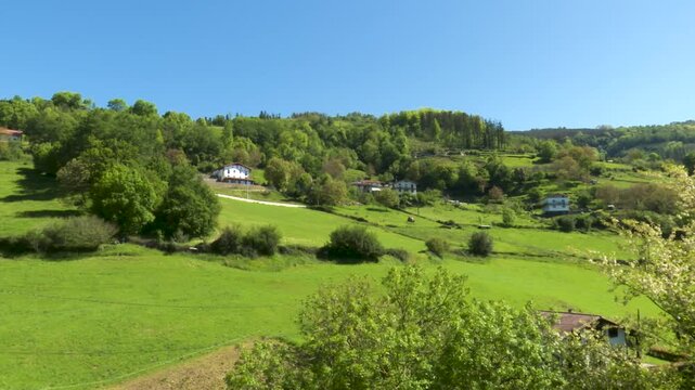 Panoramic view of basque countryside farmhouses and sloping green hills a wide
