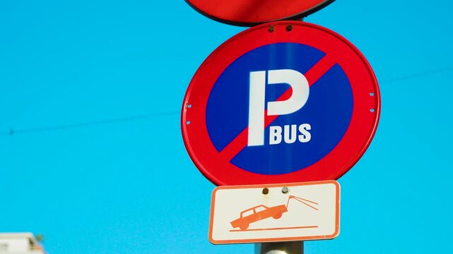 Bus no parking traffic sign with tow away warning against blue sky. Public transport restricted parking zone in Spanish city. Urban road regulation and municipal traffic infrastructure