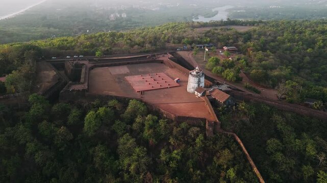 Aerial view of fort aguada lighthouse in goa india surrounded by lush jungle and river landscape at sunrise