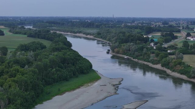 Po River near Isola Serafini, Monticelli d'Ongina, Piacenza, Emilia-Romagna, Italy, revealing exposed gravel bars, reduced river discharge and the distant Cremona skyline during the 2026 heatwave,