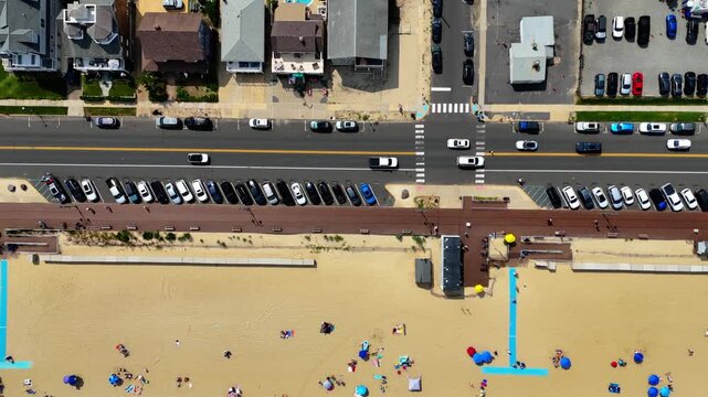 Aerial top-down pan shot captures Belmar Beach, boardwalk and active street traffic on a sunny day