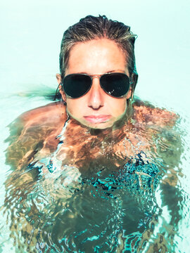 Woman Floating in Clear Water with Sunglasses