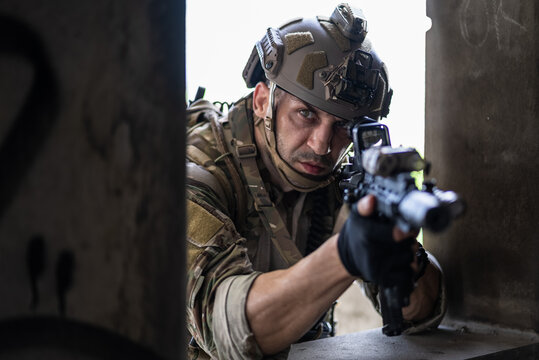 Tactical soldier aim rifle from building window in combat mission. Military mercenary look through scope sight during urban warfare operation