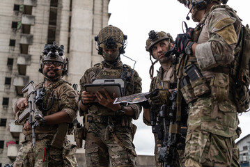 Fototapeta premium Military special force team using digital tablet and paper map for tactical urban combat planning operation near building
