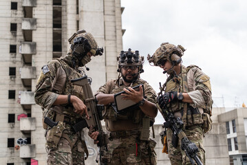 Fototapeta premium Military special force team using digital tablet and paper map for tactical urban combat planning operation near building