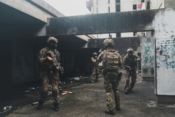 Fototapeta premium Armed special force soldier team holding rifle weapon during tactical urban combat mission inside abandoned concrete building