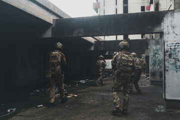 Fototapeta premium Armed special force soldier team holding rifle weapon during tactical urban combat mission inside abandoned concrete building