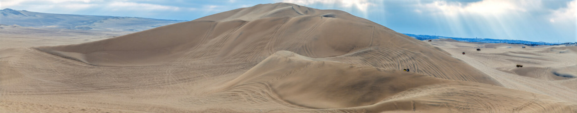 A panorama view across a large sand dunes around the oasis of Huacachina, Peru in the dry season
