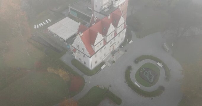 Aerial view of Topacz Castle shrouded in morning mist and autumn foliage