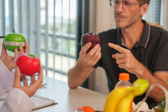 Nutrition consultant explaining healthy fruit choices to male patient in clinic