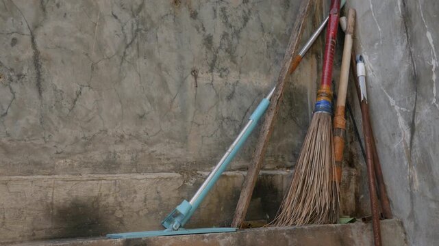 Hand Returning a Traditional Straw Broom to Storage