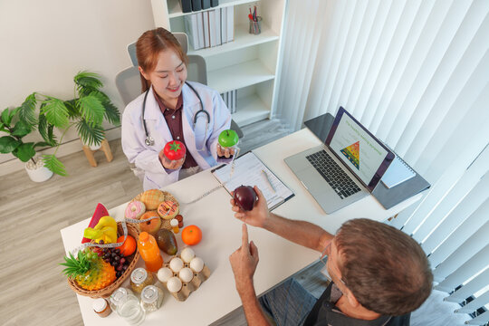 Asian female nutrition consultant explaining food pyramid and healthy diet to patient