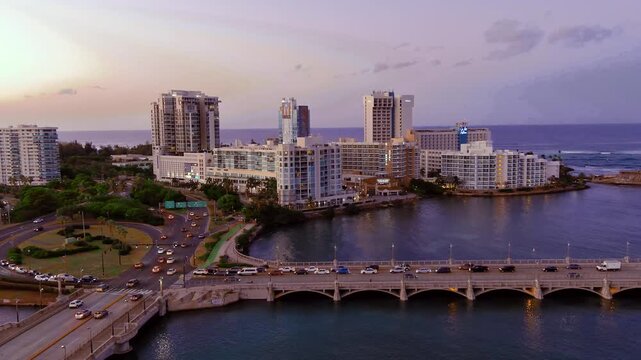 4K aerial drone shot of Dos Hermanos Bridge in the Condado area of San Juan, Puerto Rico. Shows city skyline and ocean waterway. For travel, tourism, cityscape.