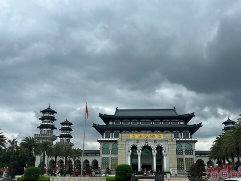 Honghe, Yunnan, China - 04 August 2026: View of Shadian Mosque with its traditional Chinese-style architecture, minarets, and palm trees under a dramatic cloudy sky.