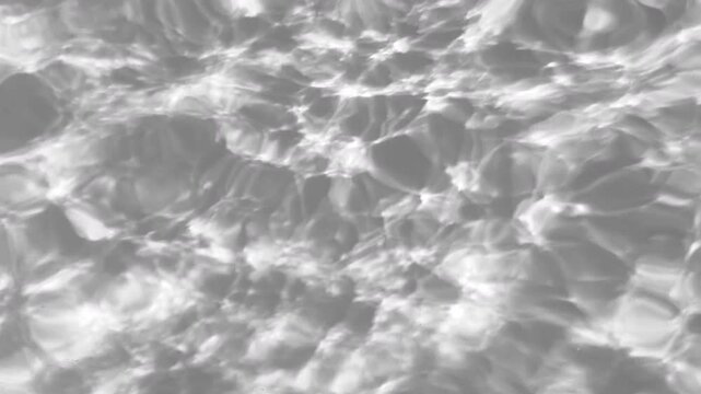 Close-up view of black and white rippling water surface with abstract reflections and moving light patterns. Gray overlay effect for video mockup. High quality 4k footage