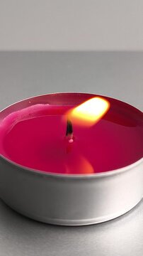 Red tealight candle is being lit with a lighter and burning with a bright flickering flame. Detailed close-up vertical video.