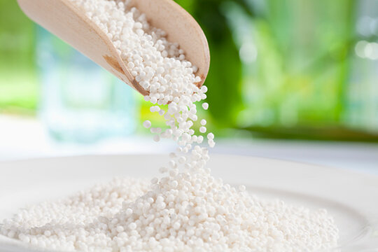 Tapioca sago pouring from wooden scoop, close up