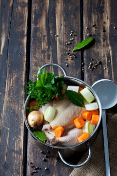 Cooking pot with raw corn-fed chicken, onion, herbs and greens