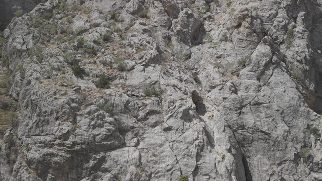 4K 10-bit cinematic drone strafe shot flying laterally in front of giant cliff walls showing hand-carved stone tunnel windows in Dark Canyon, Turkey