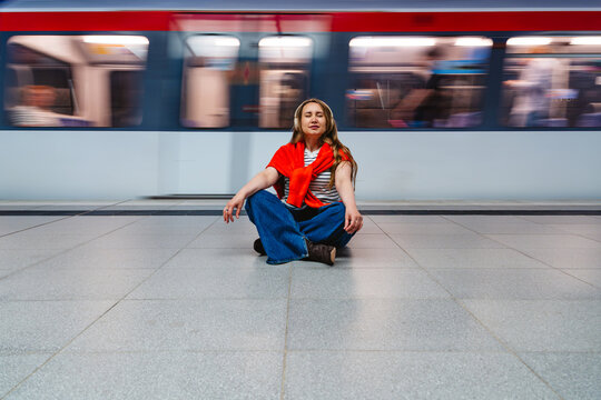 A woman finds stillness on a metro platform during her commute