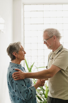 Male doctor comforting female patient indoors with a handshake