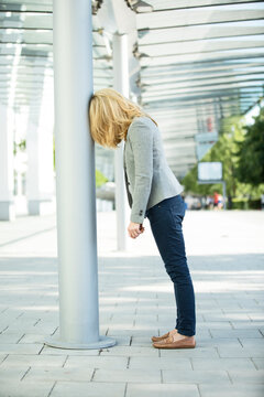 Frustated woman leaning against column