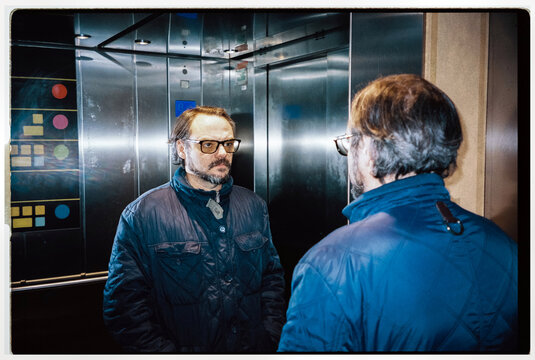 A mature man looks at his reflection in an elevator mirror