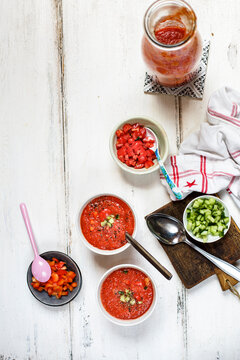 Two bowls of Gazpacho and bowls of toppings