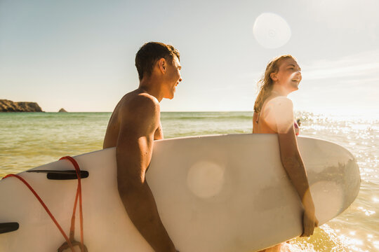 Teenage couple carrying surfboard at the sea