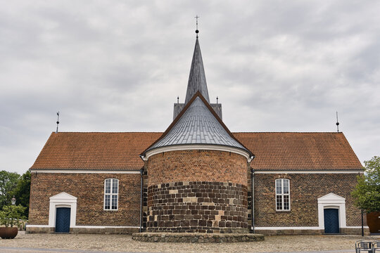 Varde, Denmark - 31 July 2026: View of St. Jacobi Kirke, a 12th-century church featuring massive granite blocks and a symmetrical brick facade under a cloudy sky.