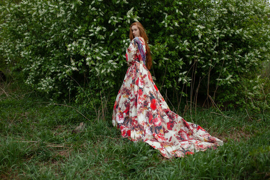 A woman wears a voluminous dress in a spring park at sunset