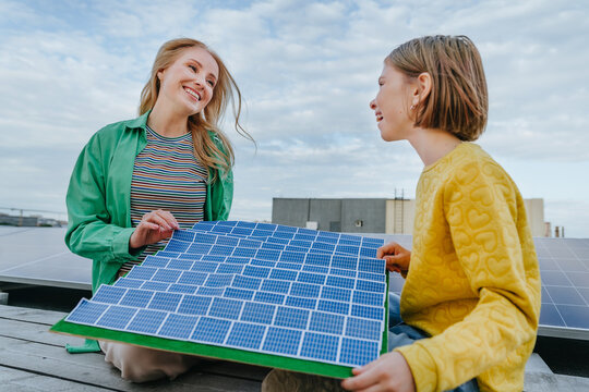 Woman and girl hold a solar panel model outdoors