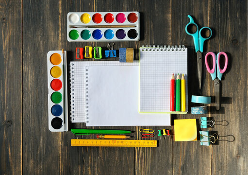 set of accessories and school stationery - pencils, watercolor palette, notebooks on wooden table. Back to school, education, Knowledge Day, 1 september, creativity, artistic art concept. flat lay