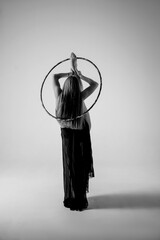 a gymnast stands with a raised leg and a hoop © Svetlana
