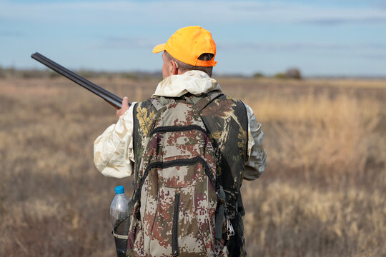 A hunter with a gun in camouflage clothing. A gentleman with a gun, medium shot, unrecognizable.