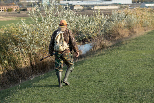 A hunter with a gun in camouflage clothing. A gentleman with a gun, medium shot, unrecognizable.