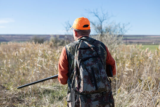 A hunter with a gun in camouflage clothing. A gentleman with a gun, medium shot, unrecognizable.