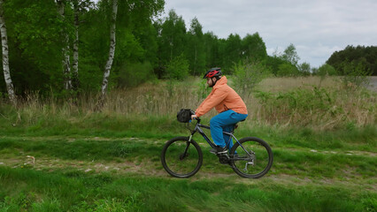 Fototapeta premium Mountain bike rider descending forest trail surrounded by trees