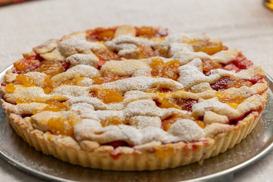 crostata dolce fatta in casa con pezzi di pesche e fragole vista di lato e da sopra