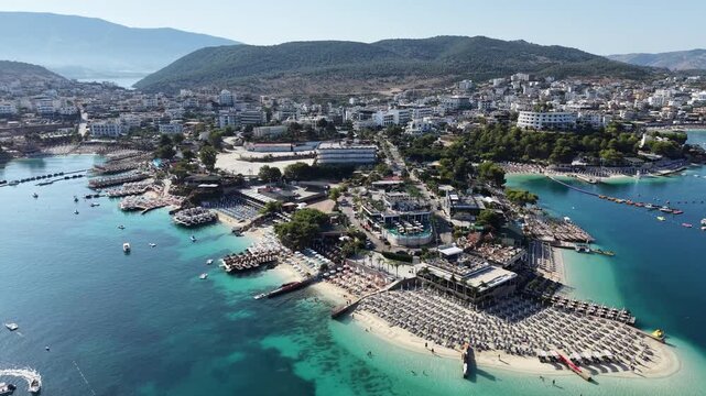 High angle drone shot of Saranda beachfront at dusk, luxury resort town in Albanian Riviera, Ionian sea. Saranda cityscape at night, pedestrian boulevard, public beach and coastal architecture, Albani