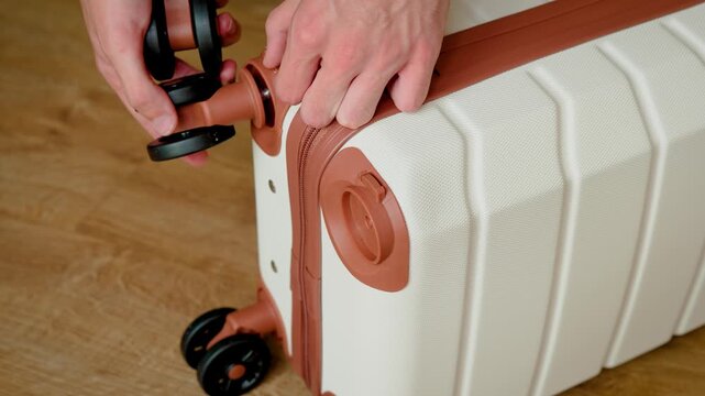 Cabin suitcase with wheel sockets after passing hand luggage size control. Traveler preparing removable wheels for continued airport journey. Space saving luggage solution for low cost airline