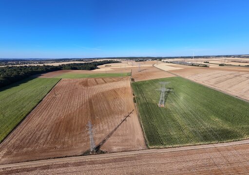 vue a&eacute;rienne panoramique des champs et des cultures pr&egrave;s de Cheni&egrave;res, en Meurthe-et-Moselle. Ciel bleu sans nuage sur ce damier agricole en Lorraine, avec des pyl&ocirc;nes &eacute;lectriques et des c&acirc;bles 2026